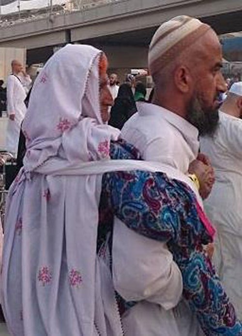 بالصور.. حاجّ باكستاني يحمل والدته المسنّة على ظهره