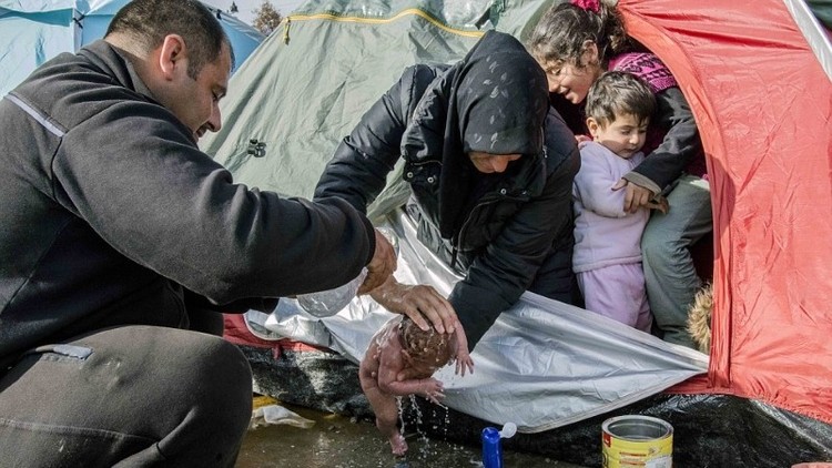 صورة صادمة للاجئة تغسل رضيعتها بمياه بركة أمطار قذرة