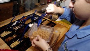 PHILADELPHIA - DECEMBER 1:  An employee tops off the cinnamon streusel container at Cereality Cereal Bar and Cafe December 1, 2004 in Philadelphia, Pennsylvania. Cereality sells almost any cereal imaginable, in their first full fledged store, on the University of Pennsylvania campus.  (Photo by William Thomas Cain/Getty Images)