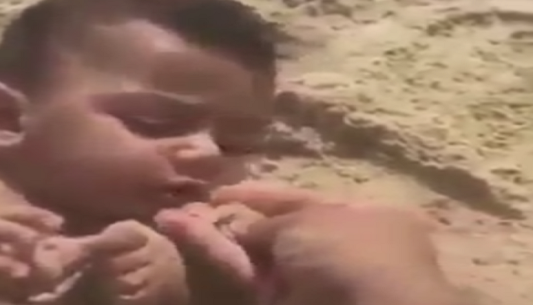 بالفيديو |وحش بشري.. يدفن طفله ويطعمه الرمال في فمه!؟
